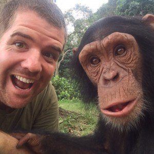 Chris Knight holds hands with a young chimpanzee.